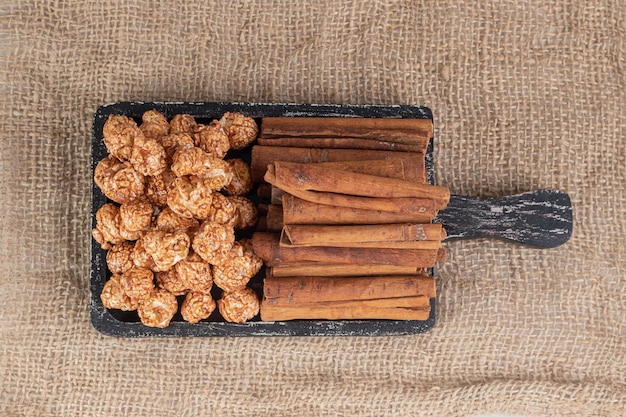 Abgenutztes Tablett mit Stapeln Popcorn-Bonbons und Zimtschnitten auf dem Textiltisch.