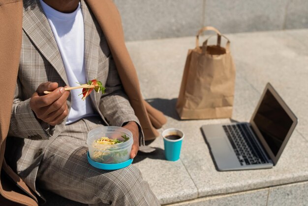 Abgeschnittenes Bild eines Geschäftsmannes beim Brunch. Mann isst Salat, trinkt Kaffee während der Arbeit. Mahlzeit, Jobkonzept