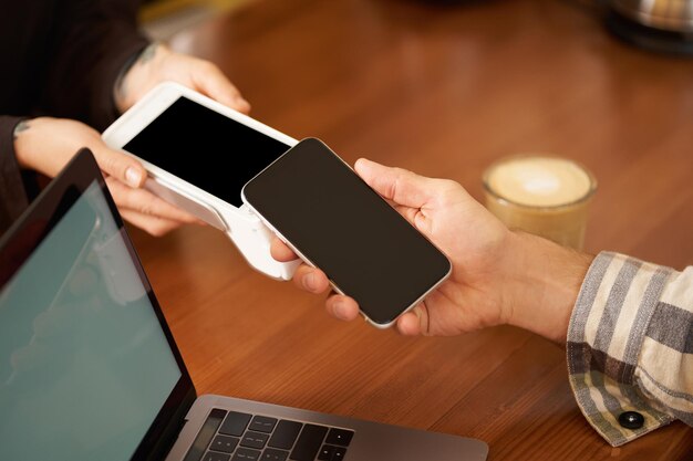 Abgeschnittenes Foto von einem Mann, der seine Hand auf ein Smartphone streckt, um das Konzept der berührungslosen Zahlung zu verfolgen