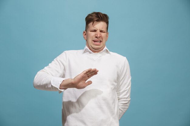 Ablehnen, Ablehnen, Zweifel Konzept. Zweifelhafter Mann mit nachdenklichem Ausdruck, der die Wahl trifft. Junger emotionaler Mann. Menschliche Emotionen, Gesichtsausdruckkonzept. Vorderseite . Studio. Auf trendigem Blau isoliert