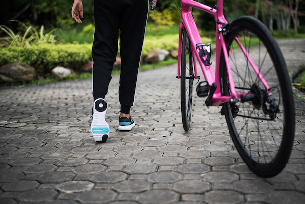 Abschluss oben der Rückseite der Frau mit Rennrad im Park. Gesundheits- und Sportkonzept.