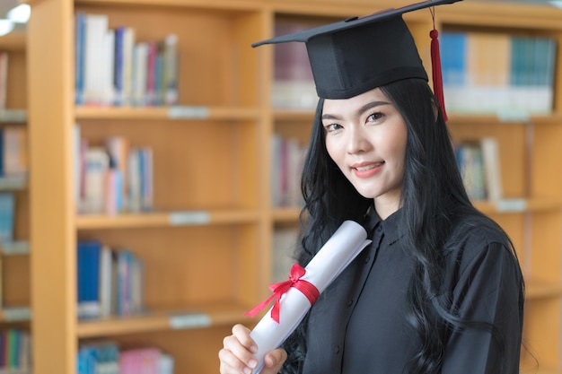 Absolventin der asiatischen universität feiert diplomabschluss mit buchselbst im hintergrund