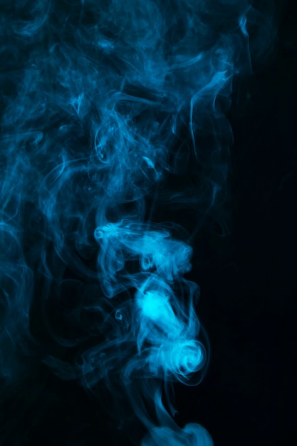 Abstrakter blauer Rauch verbreitete auf schwarzem dunklem Hintergrund