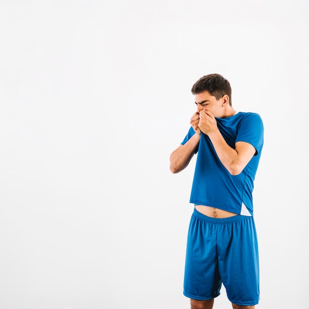 Abwischendes Gesicht des jungen Athleten mit T-Shirt