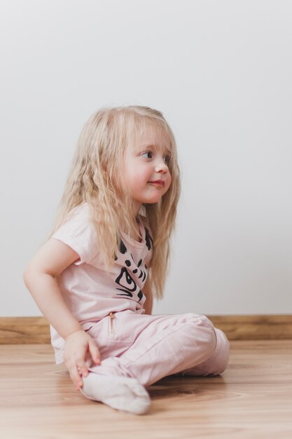 Adorable kleines Mädchen sitzt auf dem Boden