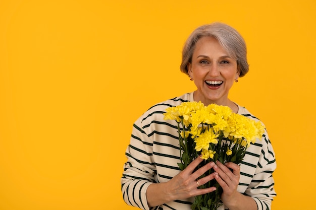 Kostenloses Foto Ältere frau der vorderansicht, die mit blumen aufwirft