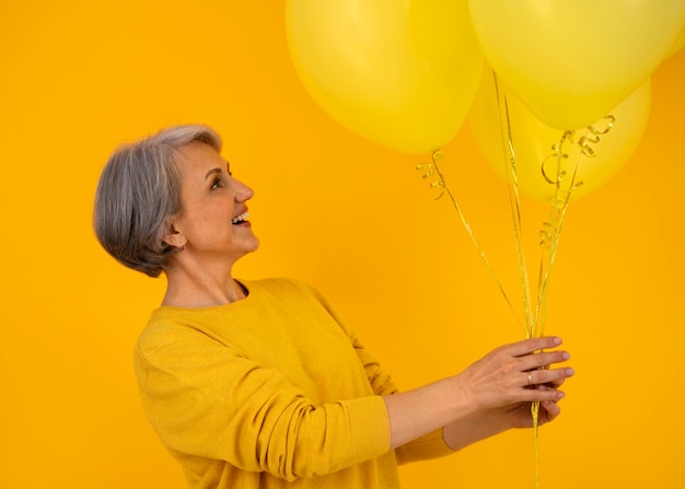 Kostenloses Foto Ältere frau des mittleren schusses, die mit ballonen aufwirft