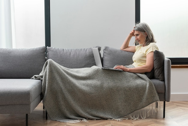 Ältere Frau zu Hause auf der Couch mit Laptop