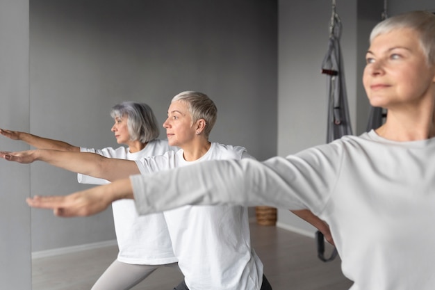 Kostenloses Foto Ältere frauen, die yoga-übungen im fitnessstudio auf yogamatten machen