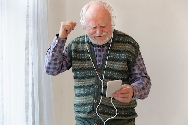 Kostenloses Foto Ältere hörende musik des niedrigen winkels auf smartphone