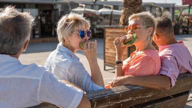 Ältere Paare, die zusammen Burger am Strand essen
