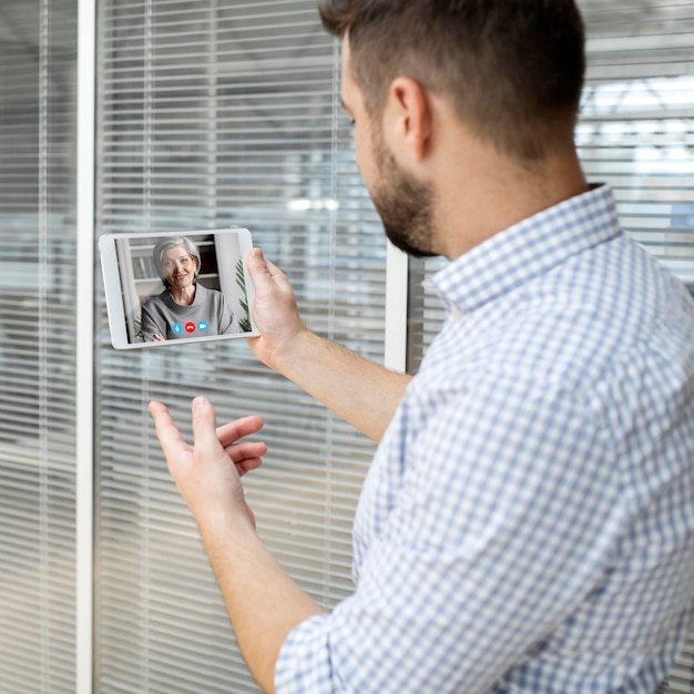 Kostenloses Foto Ältere person, die die videoanruffunktion auf ihrem gerät verwendet