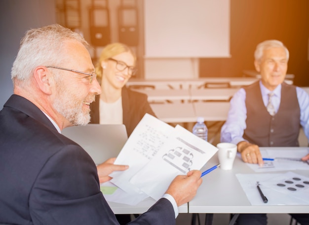 Kostenloses Foto Älterer geschäftsmann, der das papier mit seinem kollegen im büro bespricht