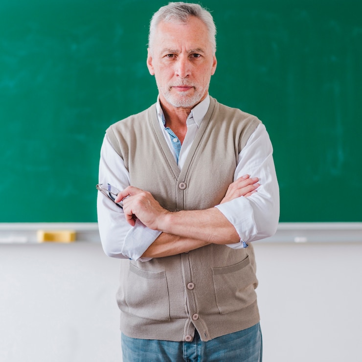Kostenlose Foto älterer männlicher professor mit den armen kreuzte stellung gegen tafel