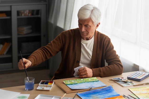 Kostenloses Foto Älterer maler, der aquarell für seine kunst verwendet