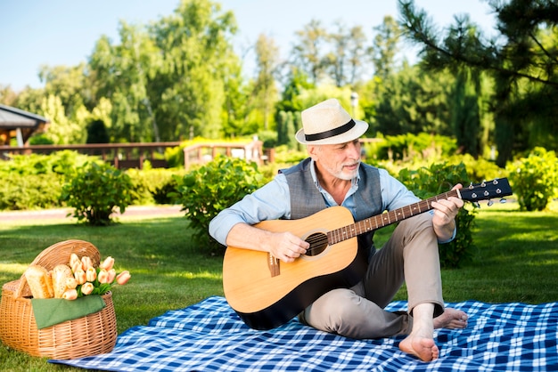 Kostenloses Foto Älterer mann, der auf gitarre spielt