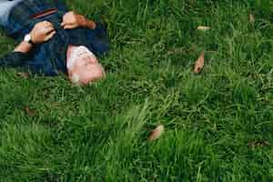 Kostenloses Foto Älterer mann, der auf grünem gras schläft