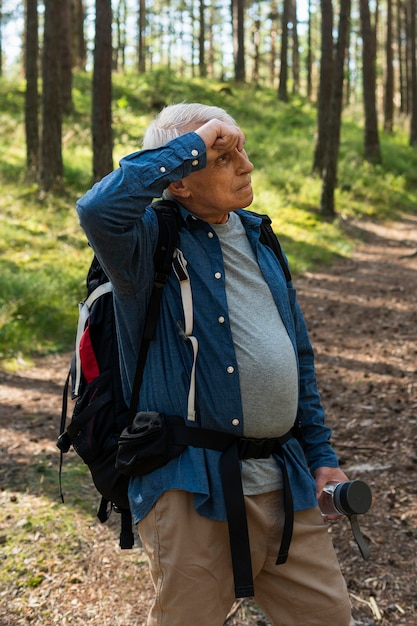 Kostenloses Foto Älterer mann, der beim rucksackwandern in der natur müde wird