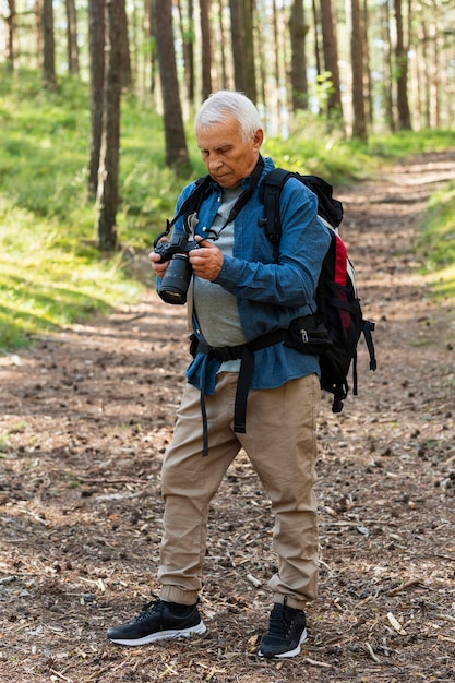 Kostenloses Foto Älterer mann, der kamera während des rucksacktourismus betrachtet