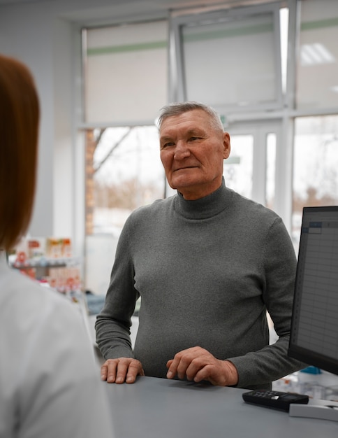 Kostenloses Foto Älterer mann, der medizin in der apotheke kauft