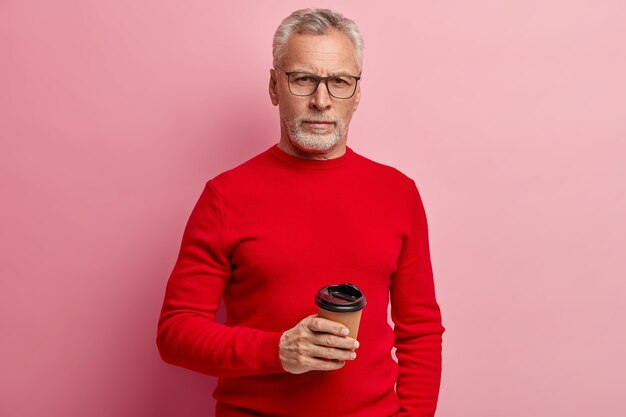 Älterer Mann, der roten Pullover und trendige Brillen trägt