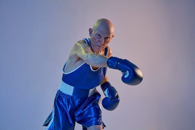 Kostenloses Foto Älterer mann, der sportbekleidungsboxen lokalisiert auf gradientenstudiowand trägt