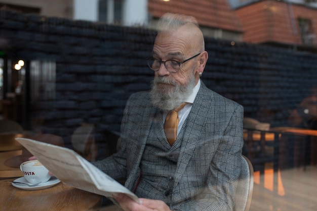 Kostenloses Foto Älterer mann des mittleren schusses, der im café liest