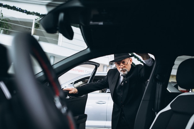 Kostenloses Foto Älterer mann in einem autosalon, der ein auto wählt