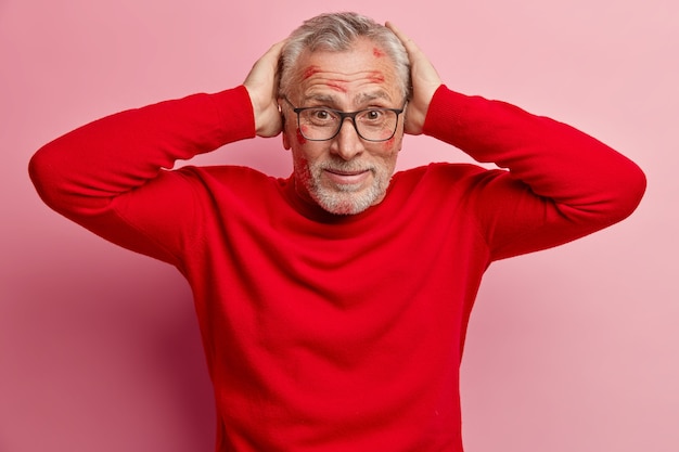 Kostenloses Foto Älterer mann mit lippenstiftflecken im gesicht und mit rotem pullover