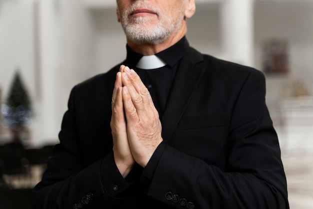 Kostenloses Foto Älterer priester, der in der kirche betet