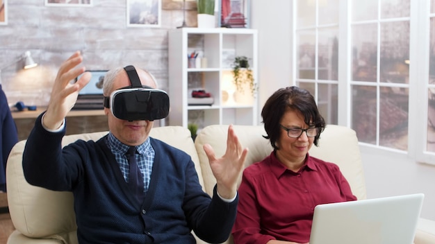 Kostenloses Foto Älteres ehepaar mit moderner technologie zum ansehen von filmen. senior mit virtual-reality-brille. alte dame mit laptop.