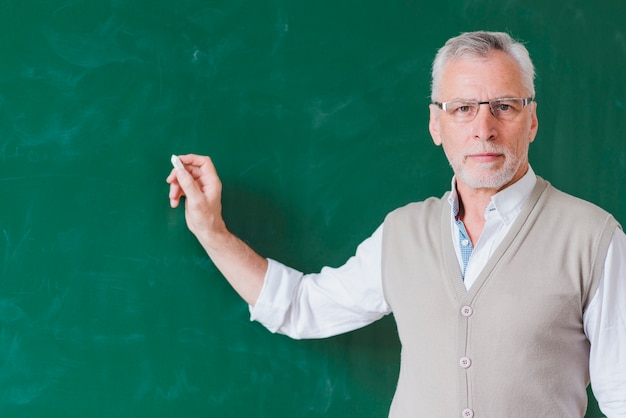 Kostenloses Foto Älteres männliches lehrerschreiben auf grüner tafel