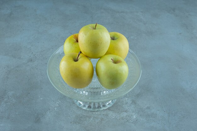 Äpfel auf einem glassockel, auf dem marmortisch.