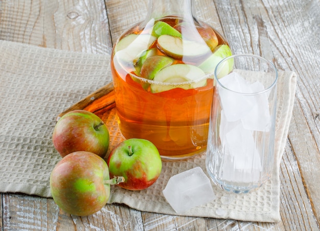Kostenloses Foto Äpfel mit saft, eiswürfel in glas, messernahaufnahme auf holz und küchentuch