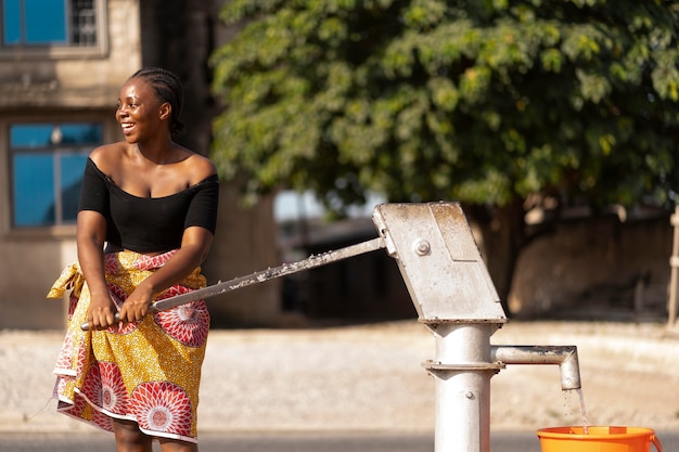 Kostenloses Foto afrikanerin gießt wasser in einen empfänger