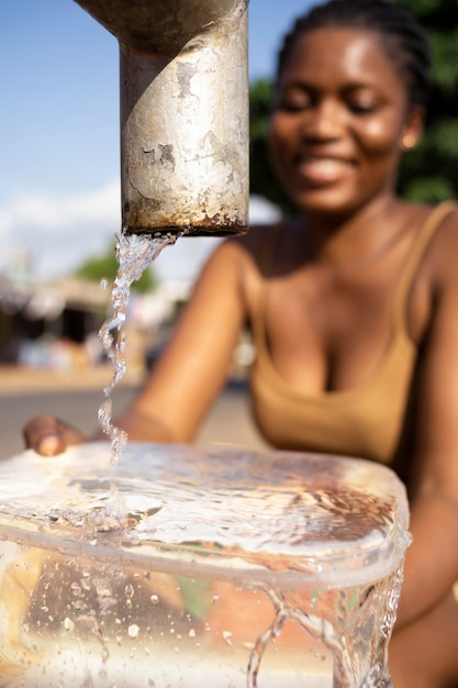 Afrikanerin gießt Wasser in einen Empfänger