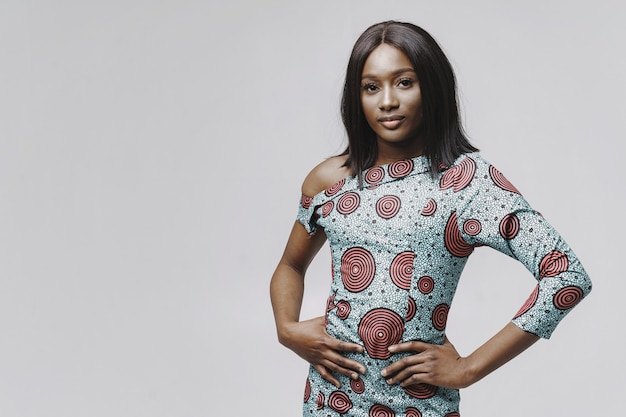 Afrikanerin in einem Studio. Weiße Wand. Frau in einem blauen Kleid.