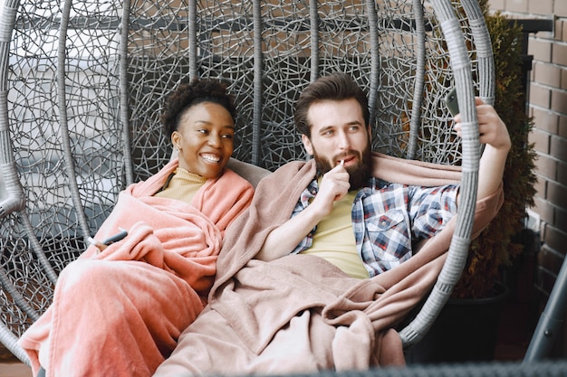 Afrikanerin mit Ehemann. Mann und Mädchen in einem Plaid. Liebhaber trinken Kaffee auf dem Balkon.