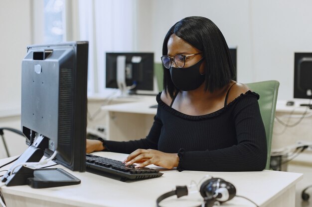 Afrikanische Frau, die im Informatikunterricht sitzt. Dame mit Brille. Studentin sitzt am Computer.