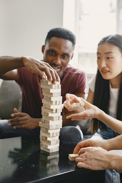 Kostenloses Foto afrikanischer junge und asiatisches mädchen, die jenga spielen brettspiel in der freizeit spielen