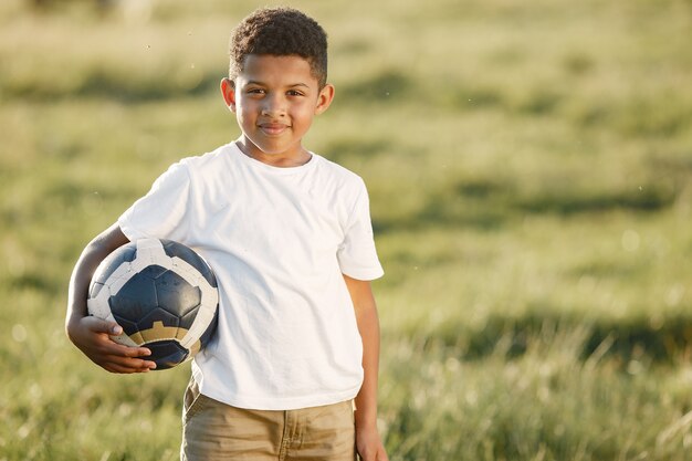 Afrikanischer kleiner Junge. Kind in einem Sommerpark. Kind mit Socer Ball.