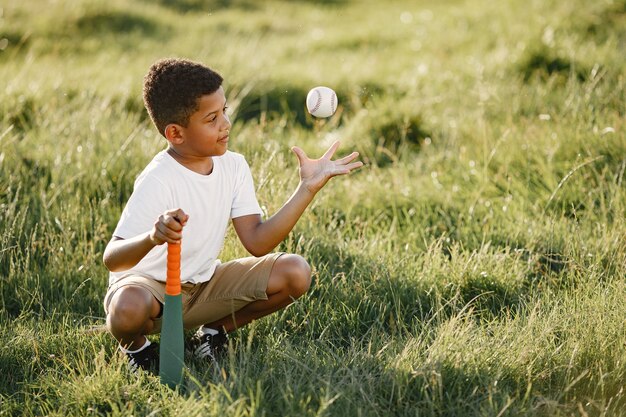 Afrikanischer kleiner Junge. Kind in einem Sommerpark. Kind spielt im American Football.