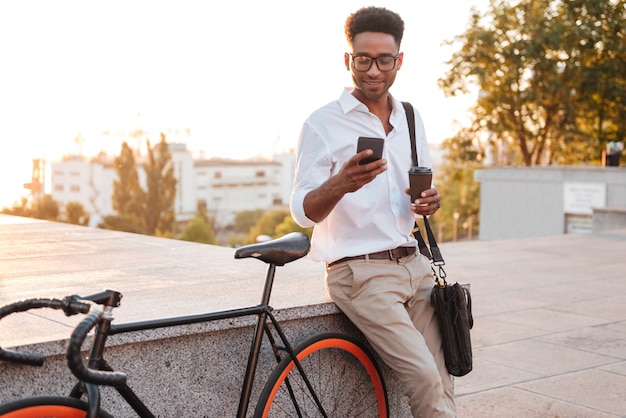 Afrikanischer mann am frühen morgen, der nahe fahrrad steht