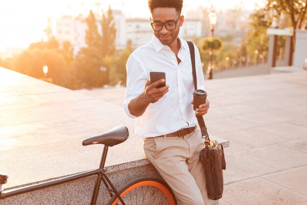 Afrikanischer Mann am frühen Morgen, der nahe Fahrrad steht