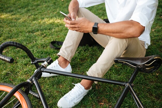 Afrikanischer Mann am frühen Morgen mit Fahrrad, das Handy hält