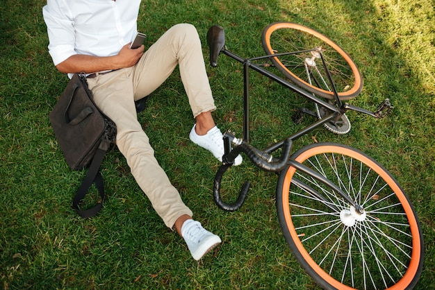 Afrikanischer Mann am frühen Morgen mit Fahrrad, das Handy hält