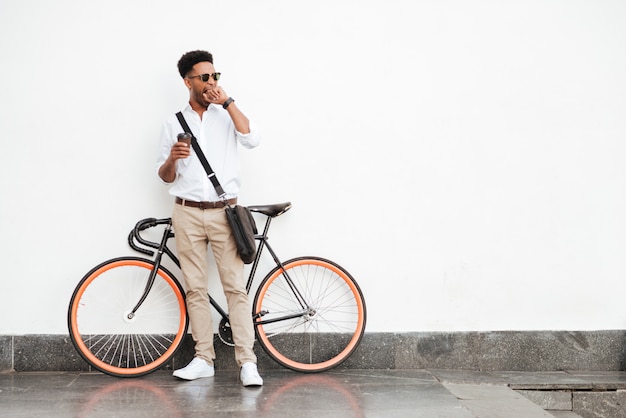 Afrikanischer Mann mit dem Fahrrad, das Kaffee trinkt.