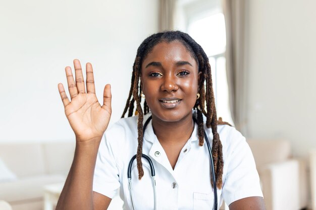 Afrikanischer omanischer Arzt, der online mit einem Patienten spricht, der einen Videoanruf tätigt und in die Kamera blickt. Junge Frau in weißer Uniform mit Stethoskop spricht Beratungs- und Therapiekonzept