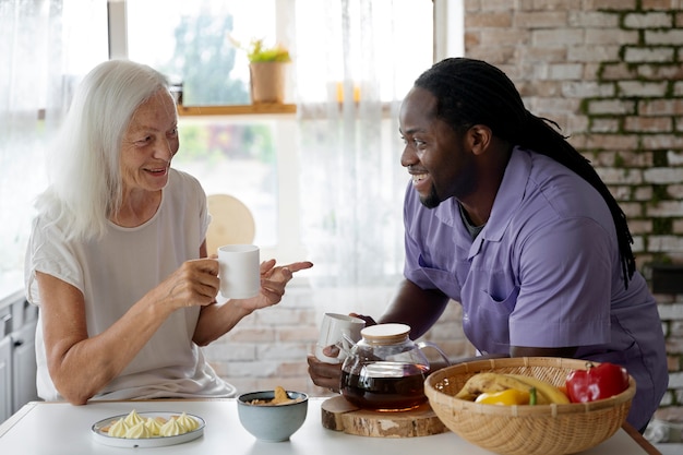 Afrikanischer Sozialarbeiter, der einer älteren Frau hilft