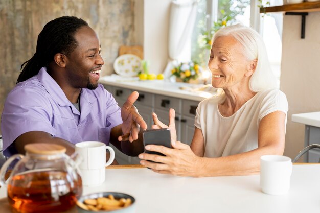 Afrikanischer Sozialarbeiter, der einer älteren Frau hilft